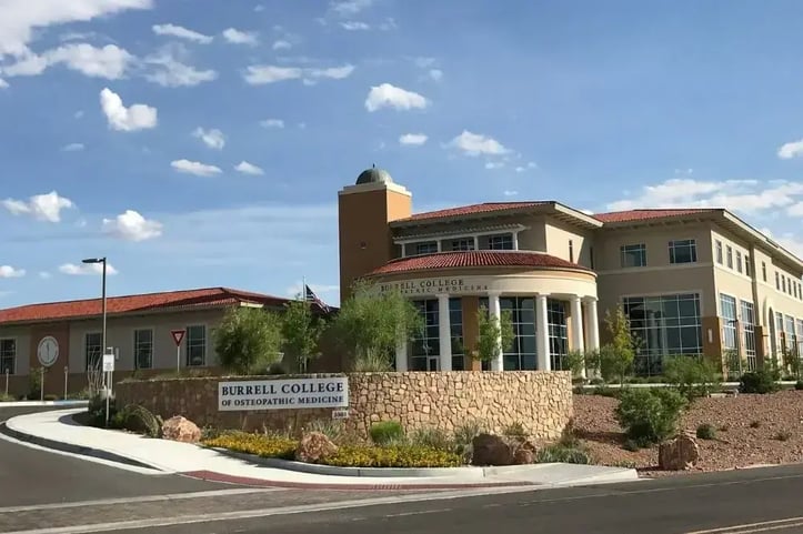 Front View of the Burrell College of Osteopathic Medicine building with a sign of the medical school on a brick half round in front of the building.
