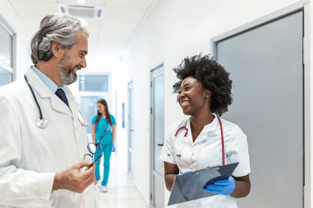 two doctors talking in a hospital hallway smiling