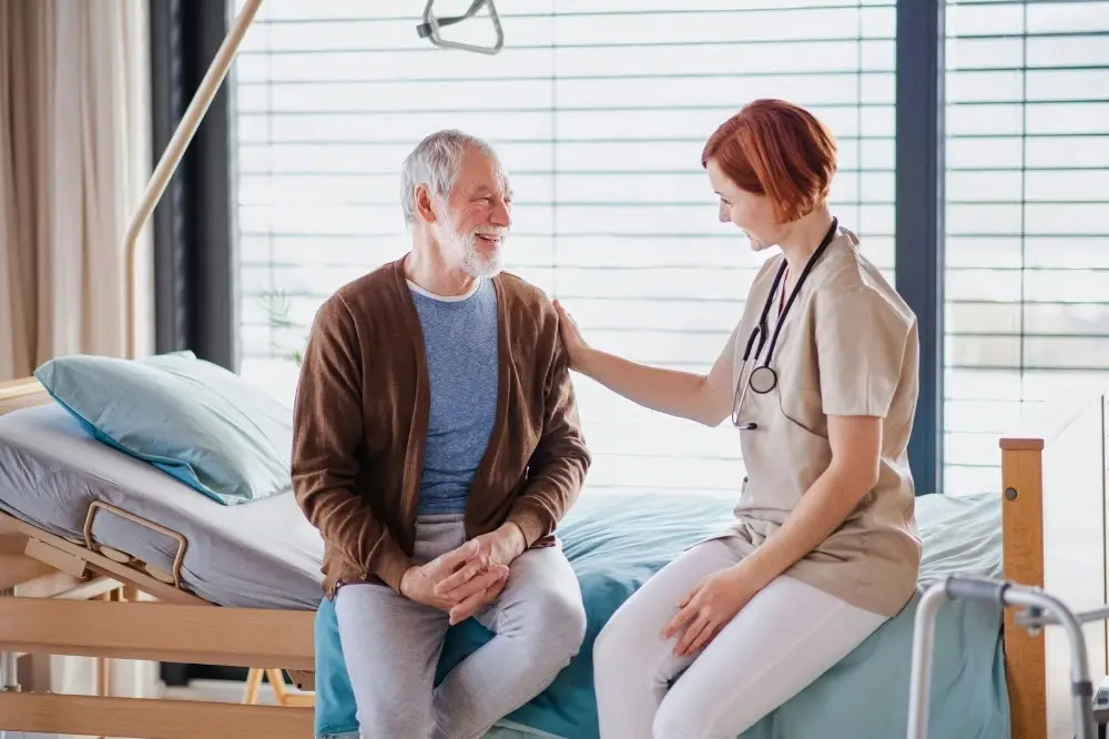 Doctor sitting on a bed next to an elderly person